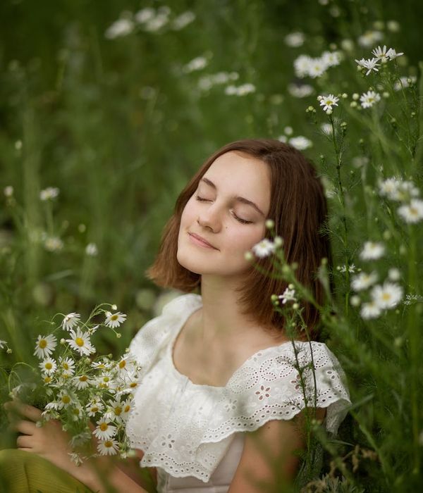 Woman with calm expression, eyes gently closed, in a serene environment.